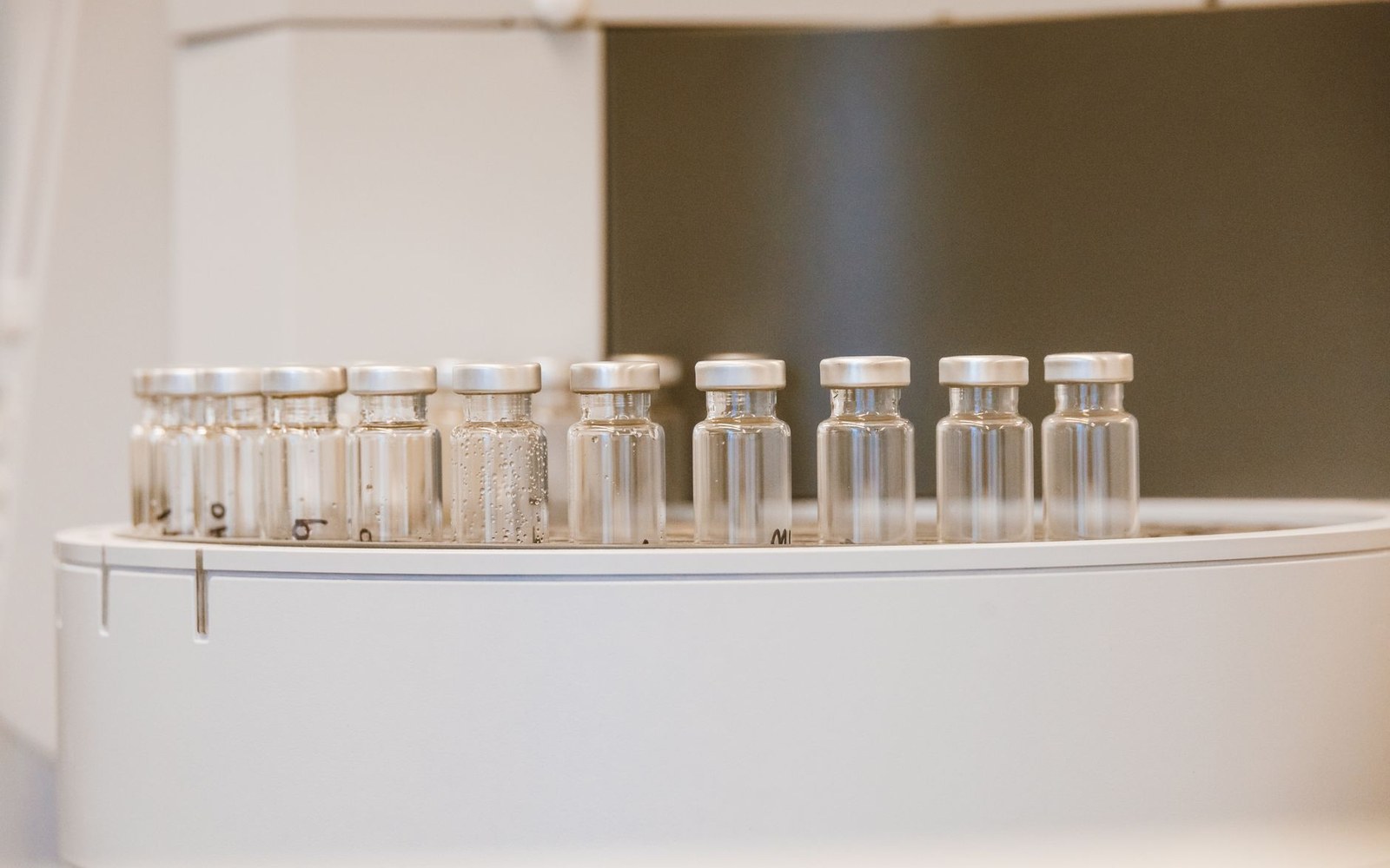 Row of sealed glass vials with metal caps lined up on a lab counter